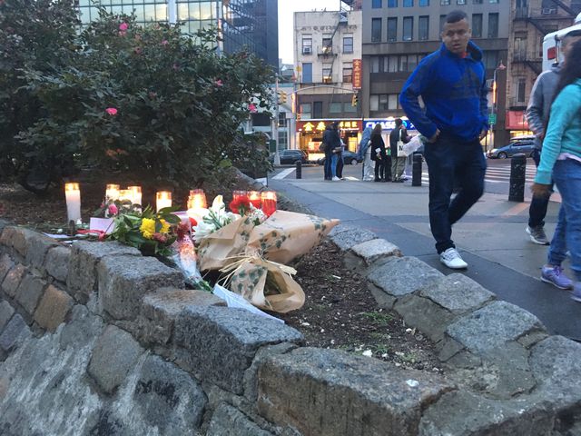 Candles and flowers are placed on a ledge in Kimlau Square, Chinatown